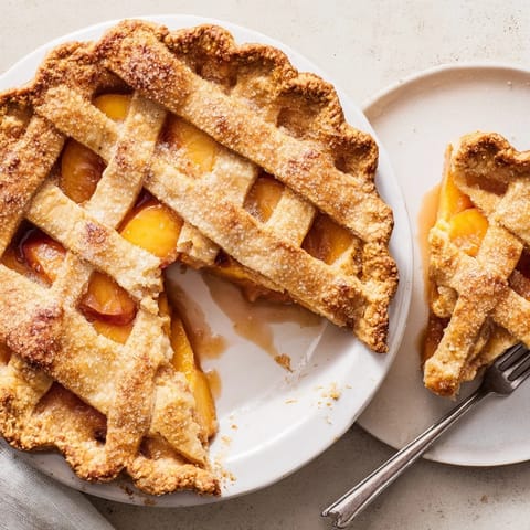 Freshly baked peach pie with a golden flaky crust cooling on a wire rack, ready to slice and serve.