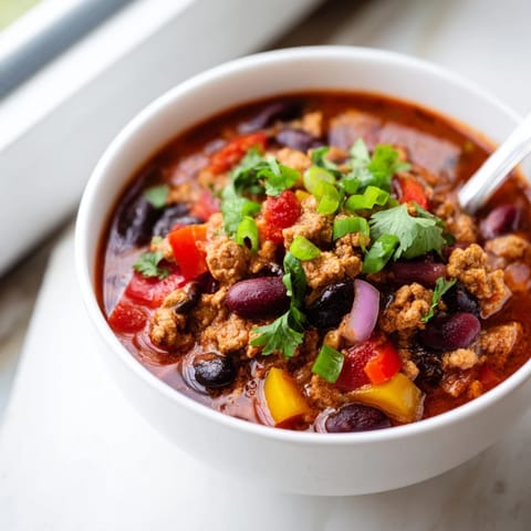 Close-up of hearty Turkey Chili in a rustic pot, revealing a rich, tomato-based broth with beans and ground turkey.