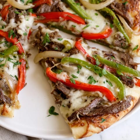 Golden melted provolone and mozzarella cover the Philly Cheesesteak Pizza, loaded with tender steak and sautéed peppers.