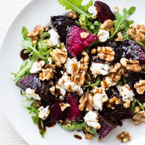 A vibrant Roasted Beet Goat Cheese Salad showcases ruby-red beet wedges, creamy crumbled goat cheese, and toasted walnuts on fresh arugula.  