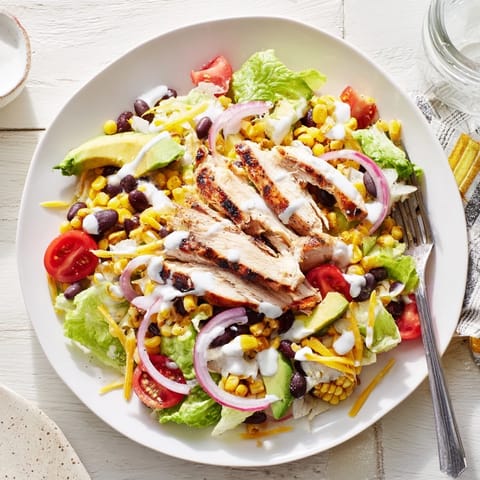 BBQ Chicken Salad features tender sliced chicken, charred corn, and avocado on a colorful bowl.