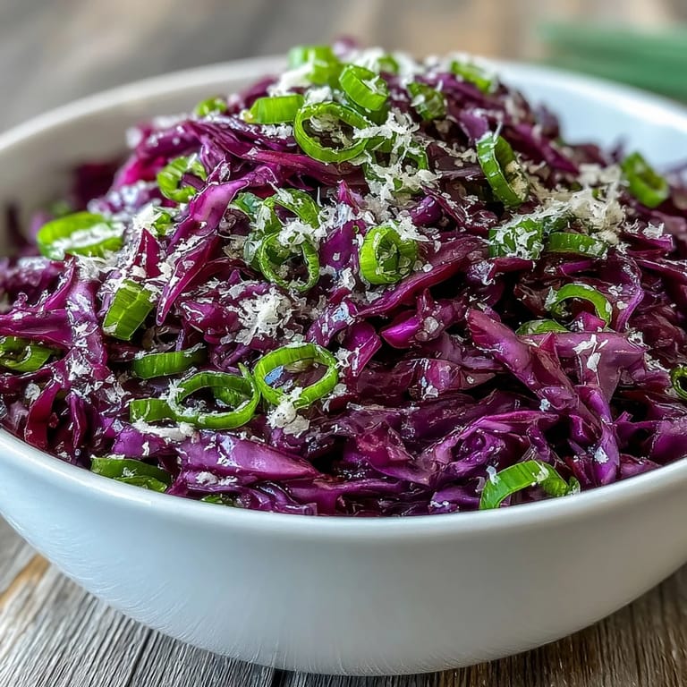 A large bowl of bright Red Cabbage Coleslaw with Apple and Parmesan next to grilled chicken.