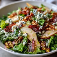 Crispy prosciutto and blue cheese crumbles top a vibrant Frisée Pear Blue Cheese Bowl with ripe pear slices.